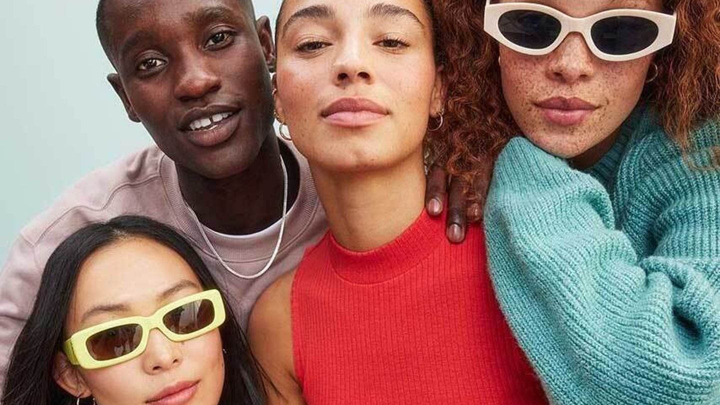 Gruppe von Freund:innen, die selbstbewusst in bunten Outfits und trendigen Sonnenbrillen posieren