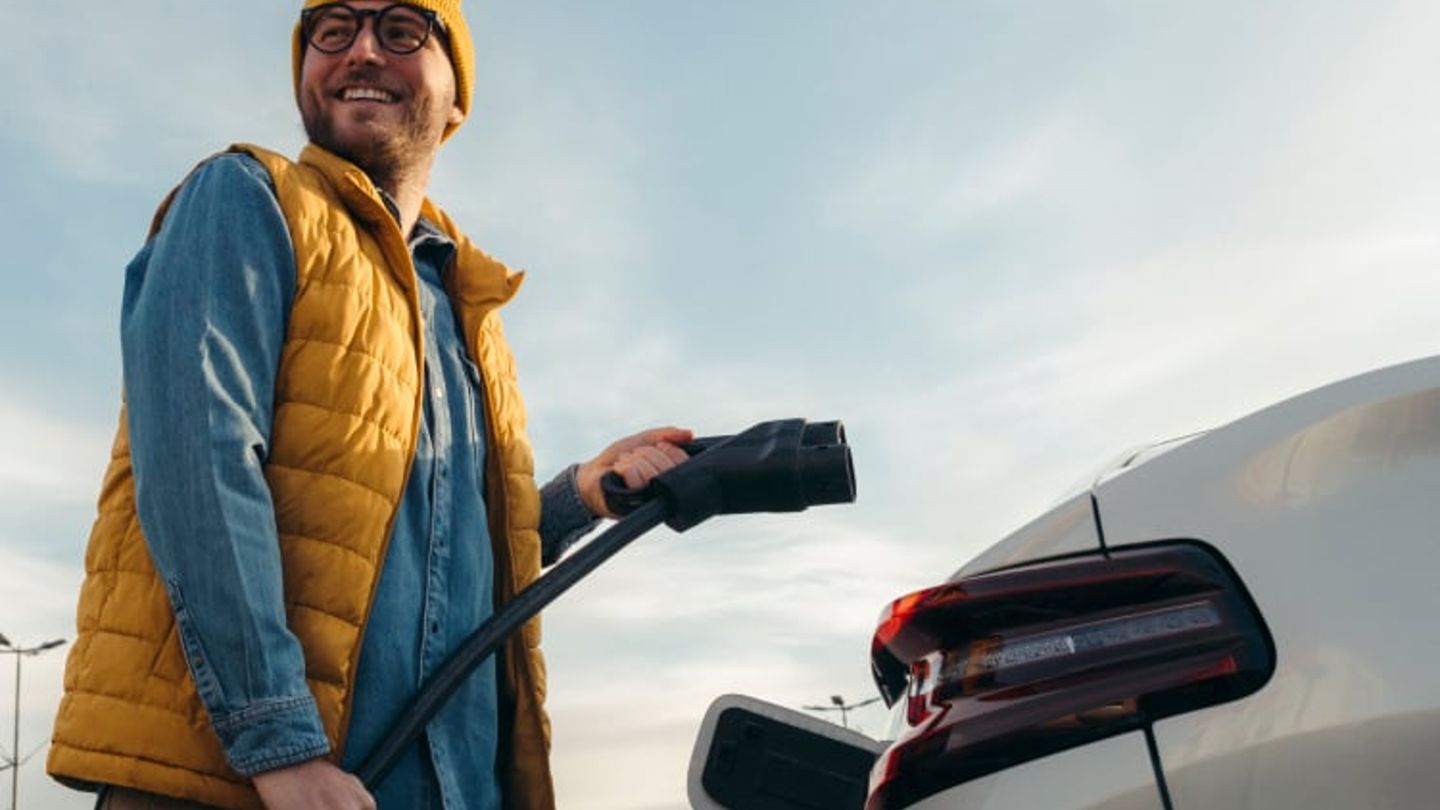 Image shows a man getting ready to charge his car. Audi, and PHD logos are featured at the top left corner of the image.