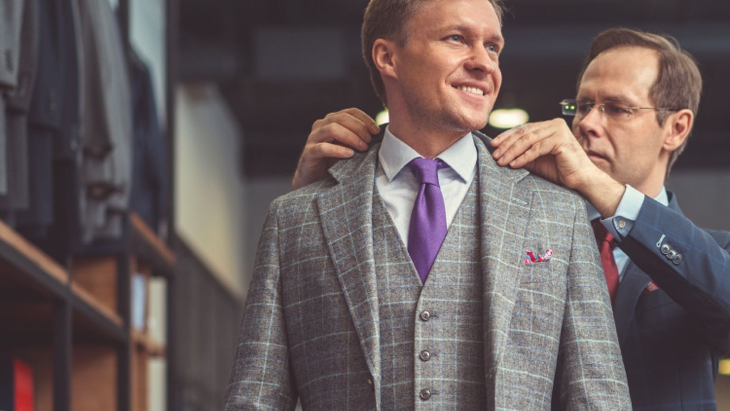 Sales associate adjusting a male in his suit from Men's Wearhouse