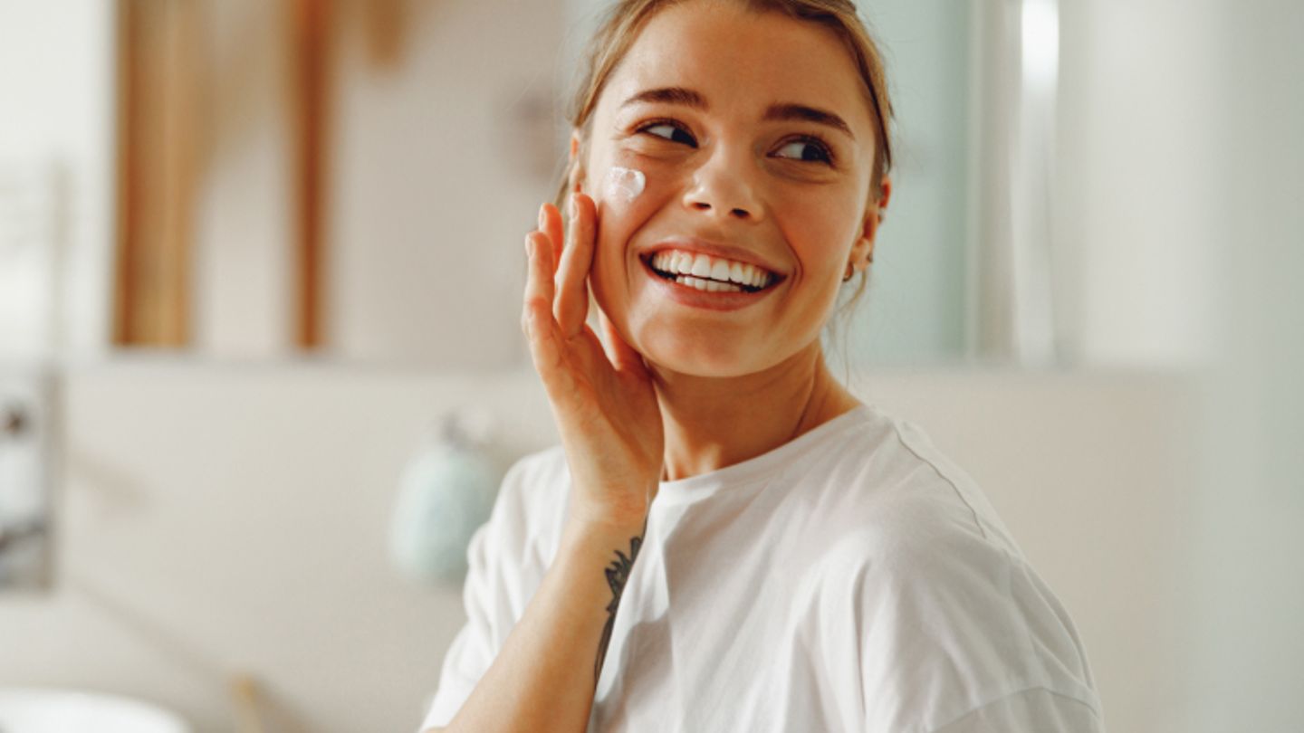 A woman applies Neutrogena cream to her face