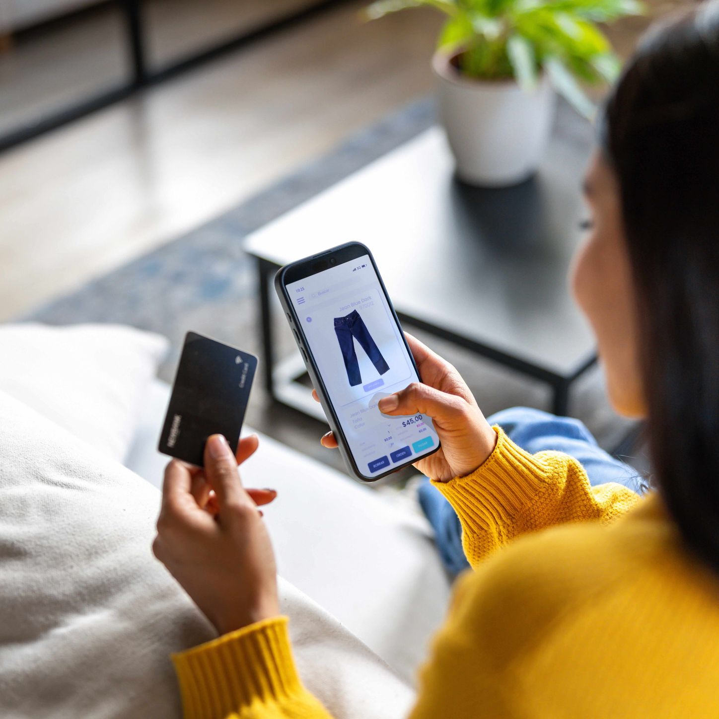 Person shopping online with a smartphone and credit card while viewing a product on a tablet.