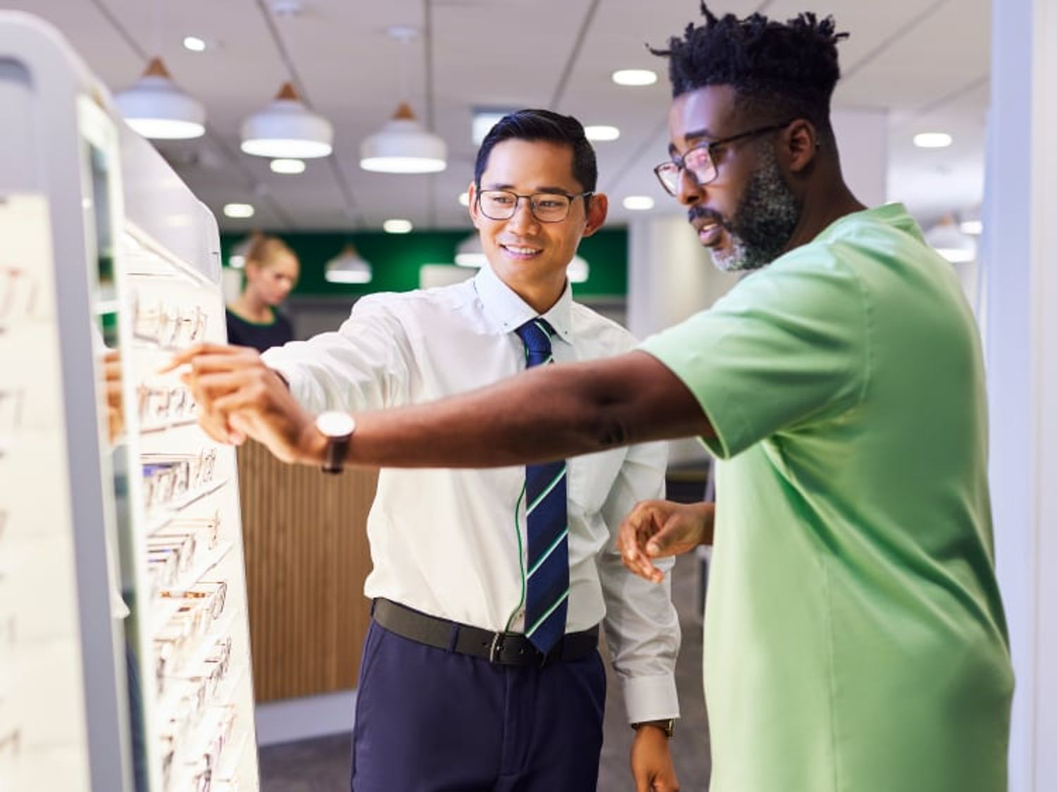 Two people wearing glasses at eyeglass store picking out lenses