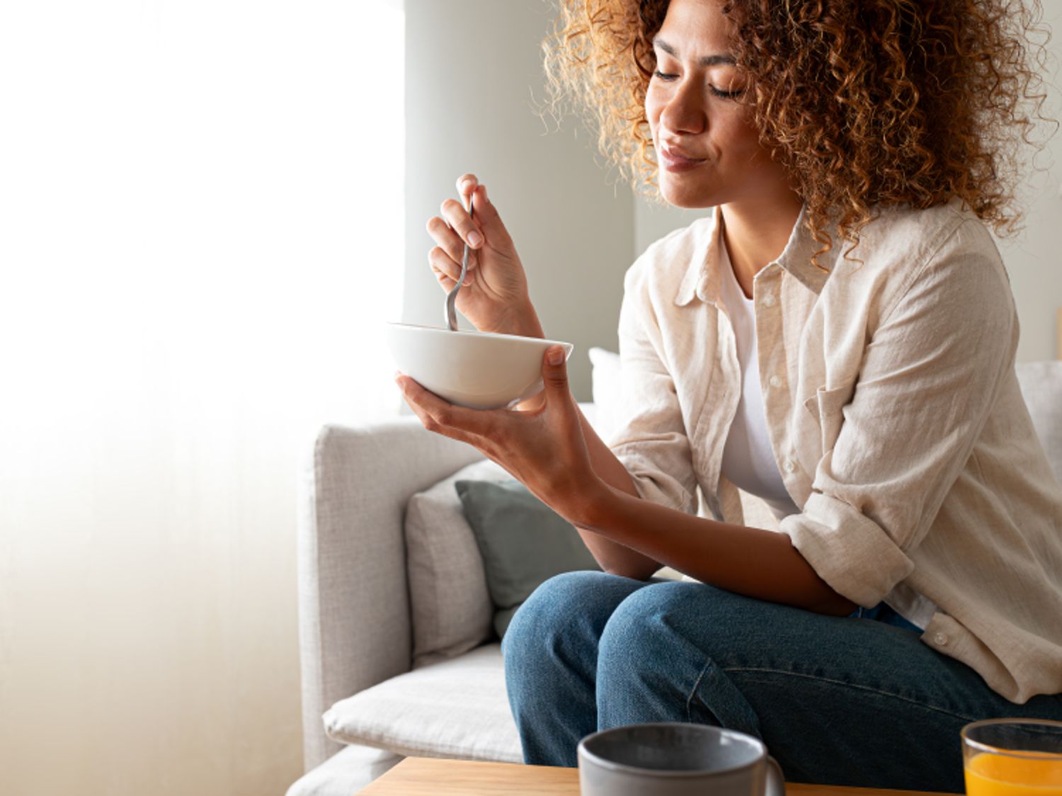 Woman sitting down and eating a bowl of Cheerios