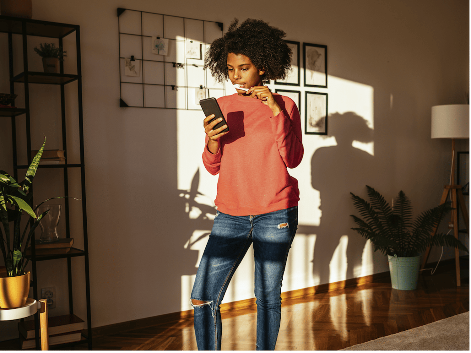 スマートフォンを操作しながら歯を磨くティーンエイジャーの画像