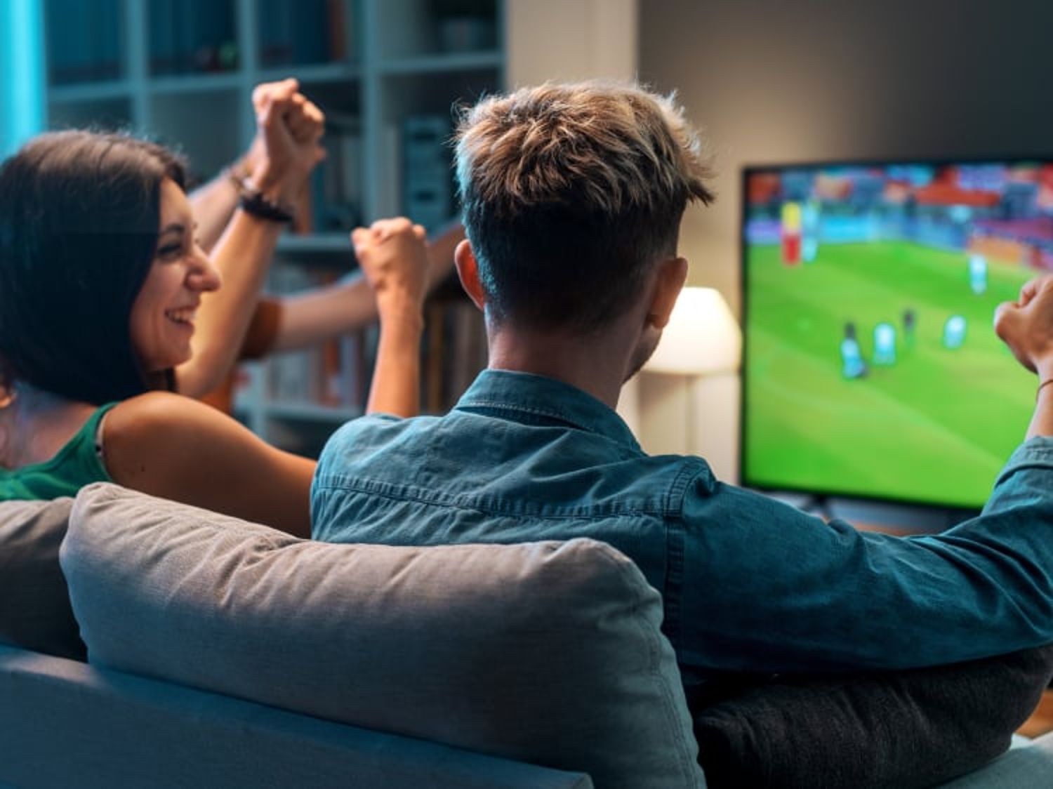Two people watching live sports on their television