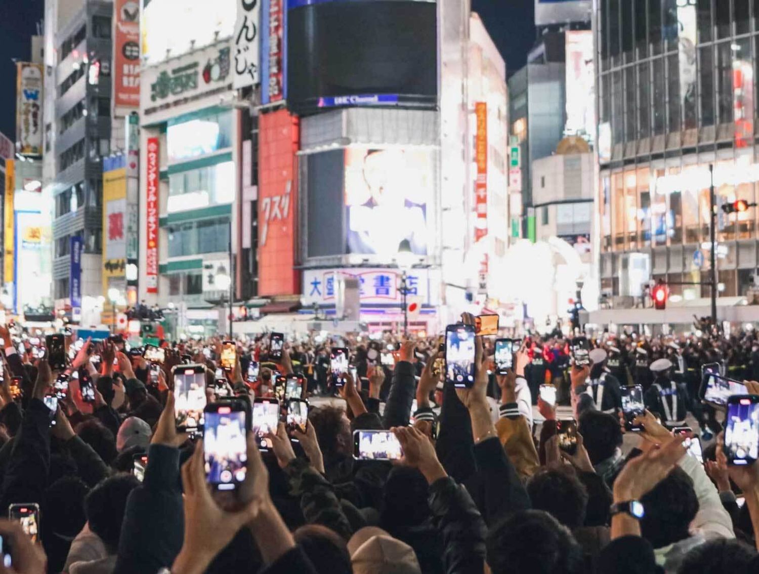 A crowd of people recording Times Square on their phones