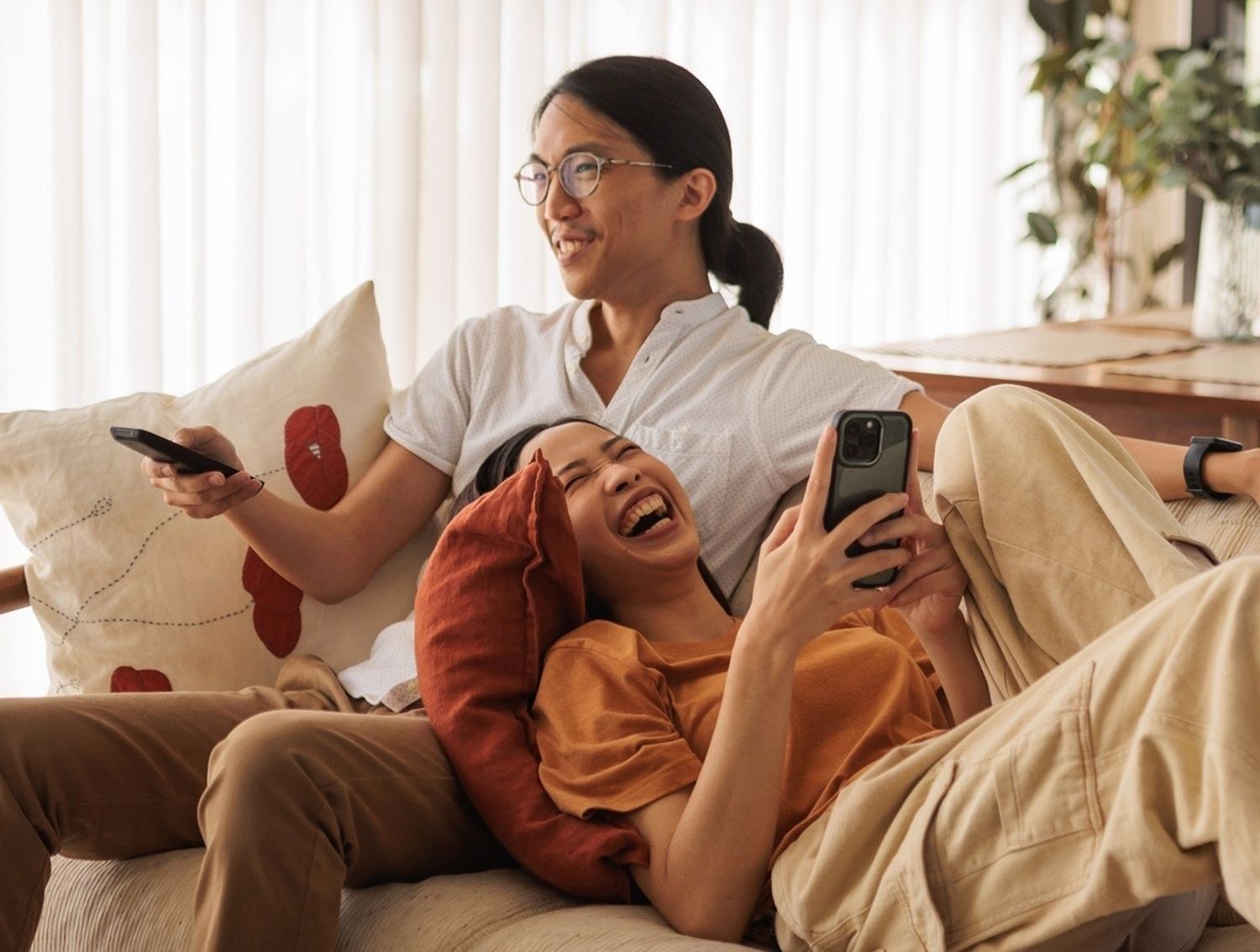 Two people relaxing on a sofa, with devices