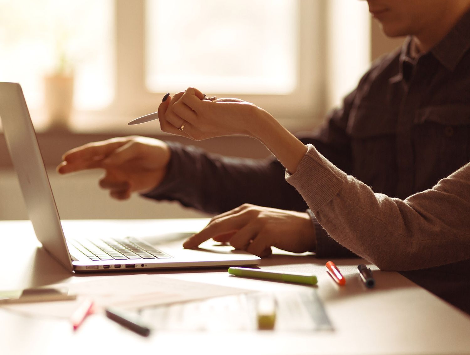 Two hands working at a laptop together