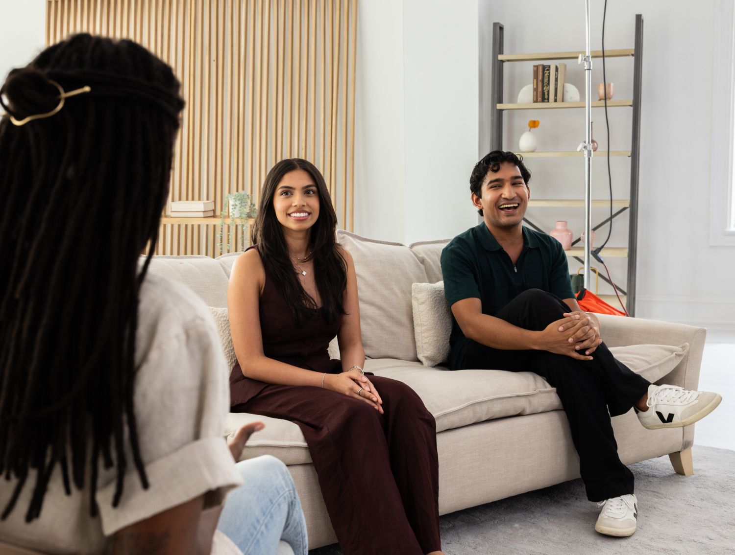 Two people on a couch being interviewed by another person.