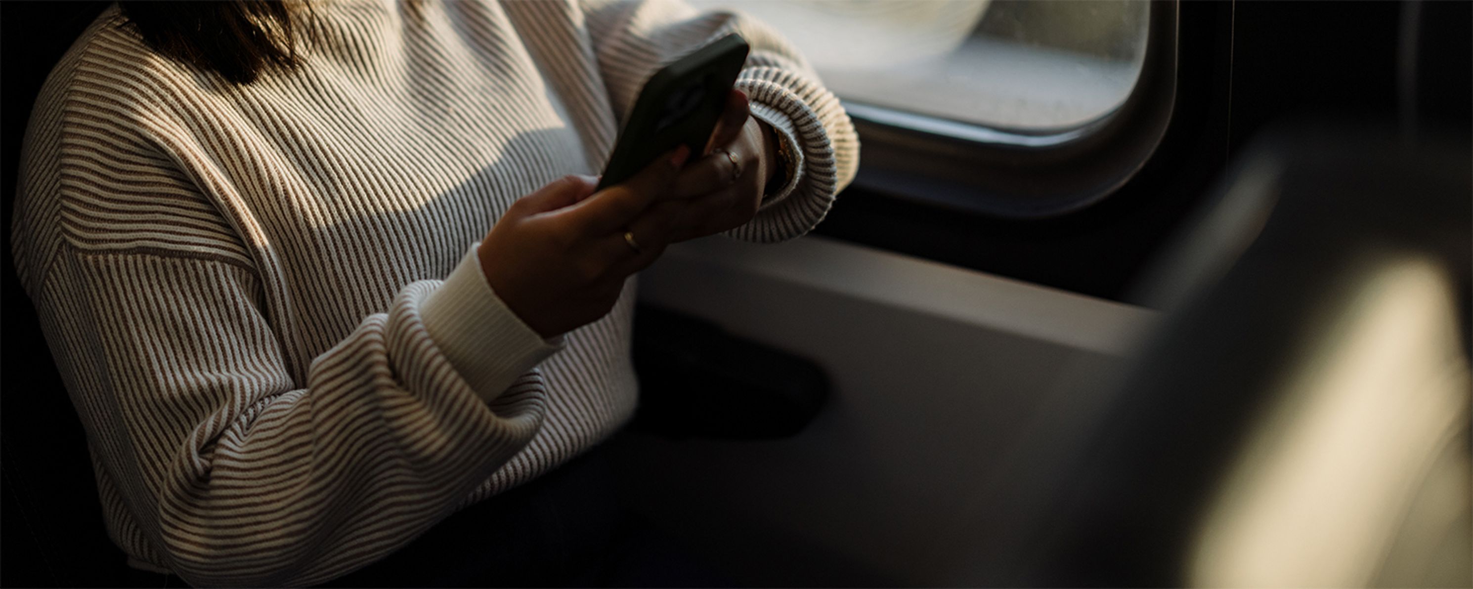 A person sits on public transportation holding a phone.