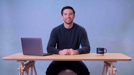 Man sitting at a desk and smiling, still from a Resource Desk video
