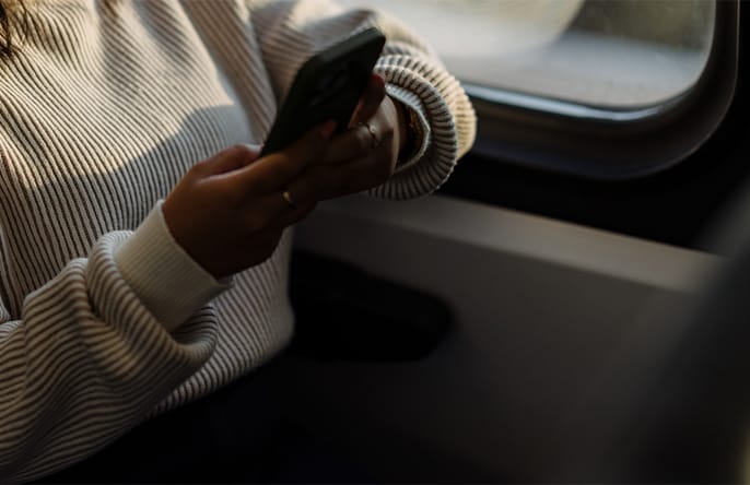 A person sits on public transportation holding a phone.