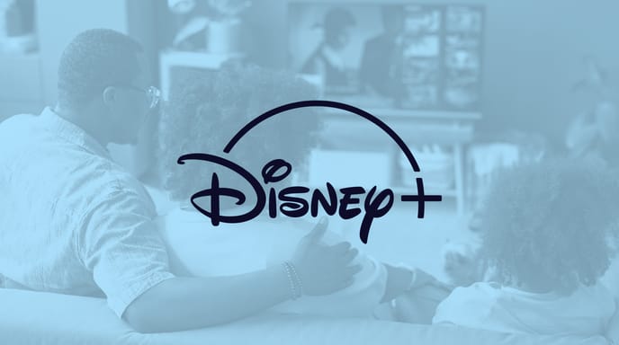 A family sits on a couch watching TV with a light blue overlay and the Disney+ logo displayed over top.