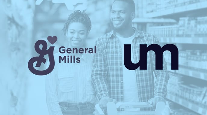 Smiling adult couple shopping together in a grocery store aisle, pushing a cart filled with items.