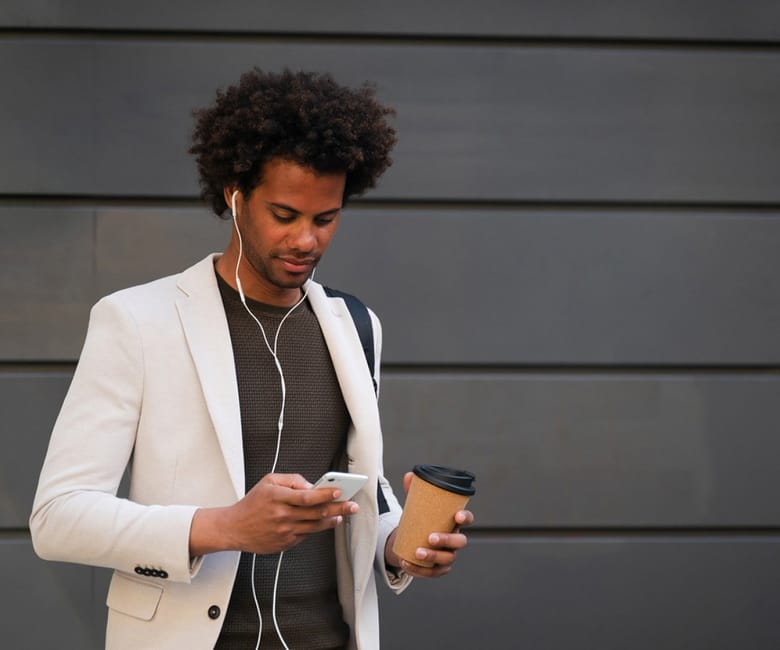 Man looking down at his phone and holding a coffee
