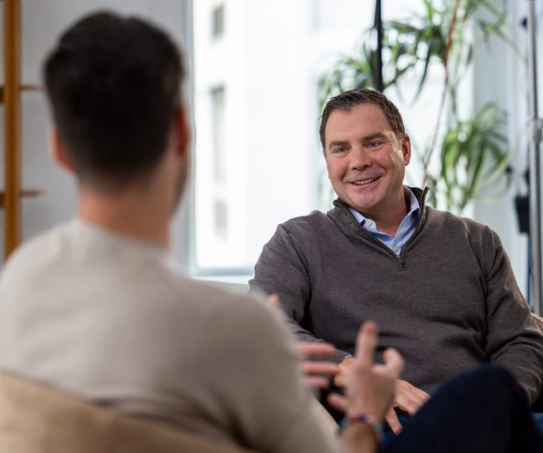 Dave DeRobbio seated in discussion during filmed interview in modern office setting