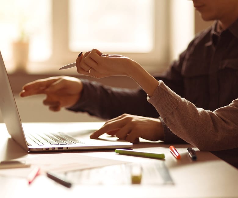 Two hands working at a laptop together