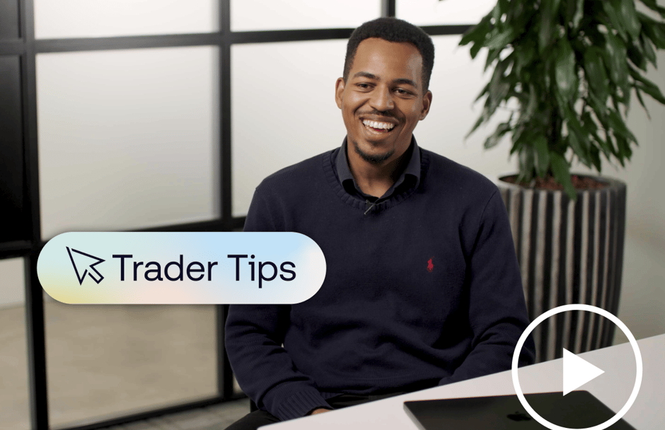 Man smiling in an office setting with a laptop on the desk and a plant in the background.