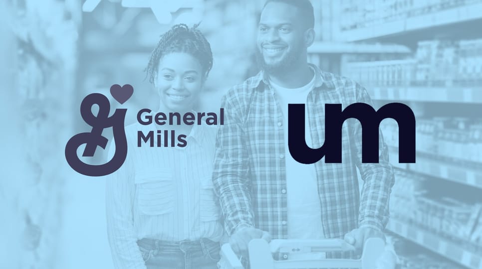 Smiling adult couple shopping together in a grocery store aisle, pushing a cart filled with items.