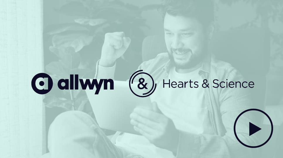 A man sitting in a chair looks excited and celebrates with a fist pump while using a tablet.