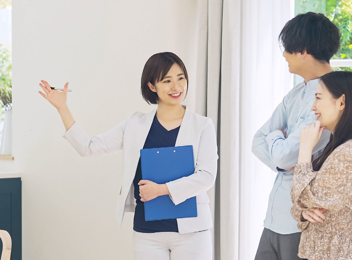 Couple with a real estate agent, holding a clip board and viewing a house.