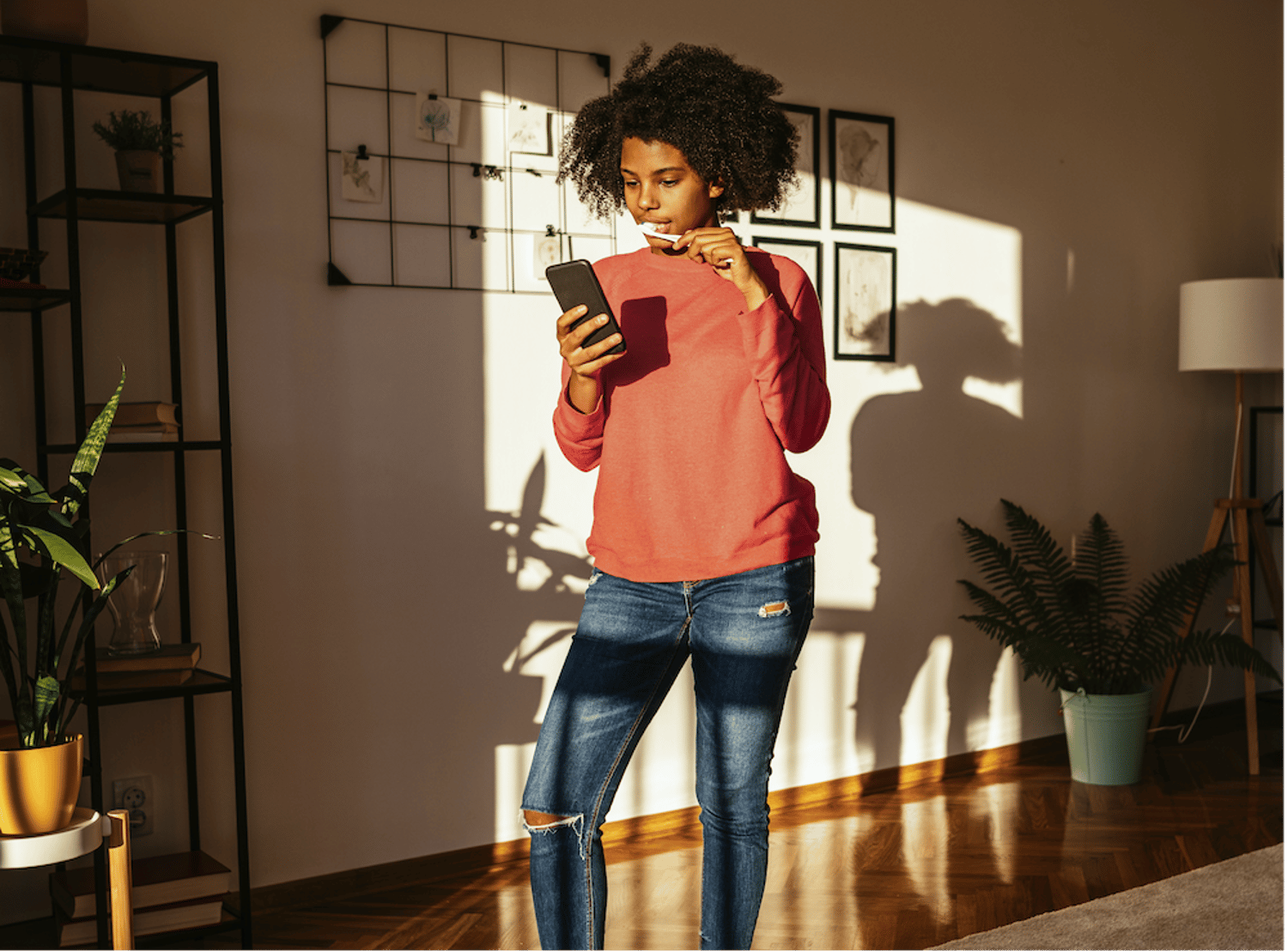 Image shows a teenager brushing their teeth while on their phone