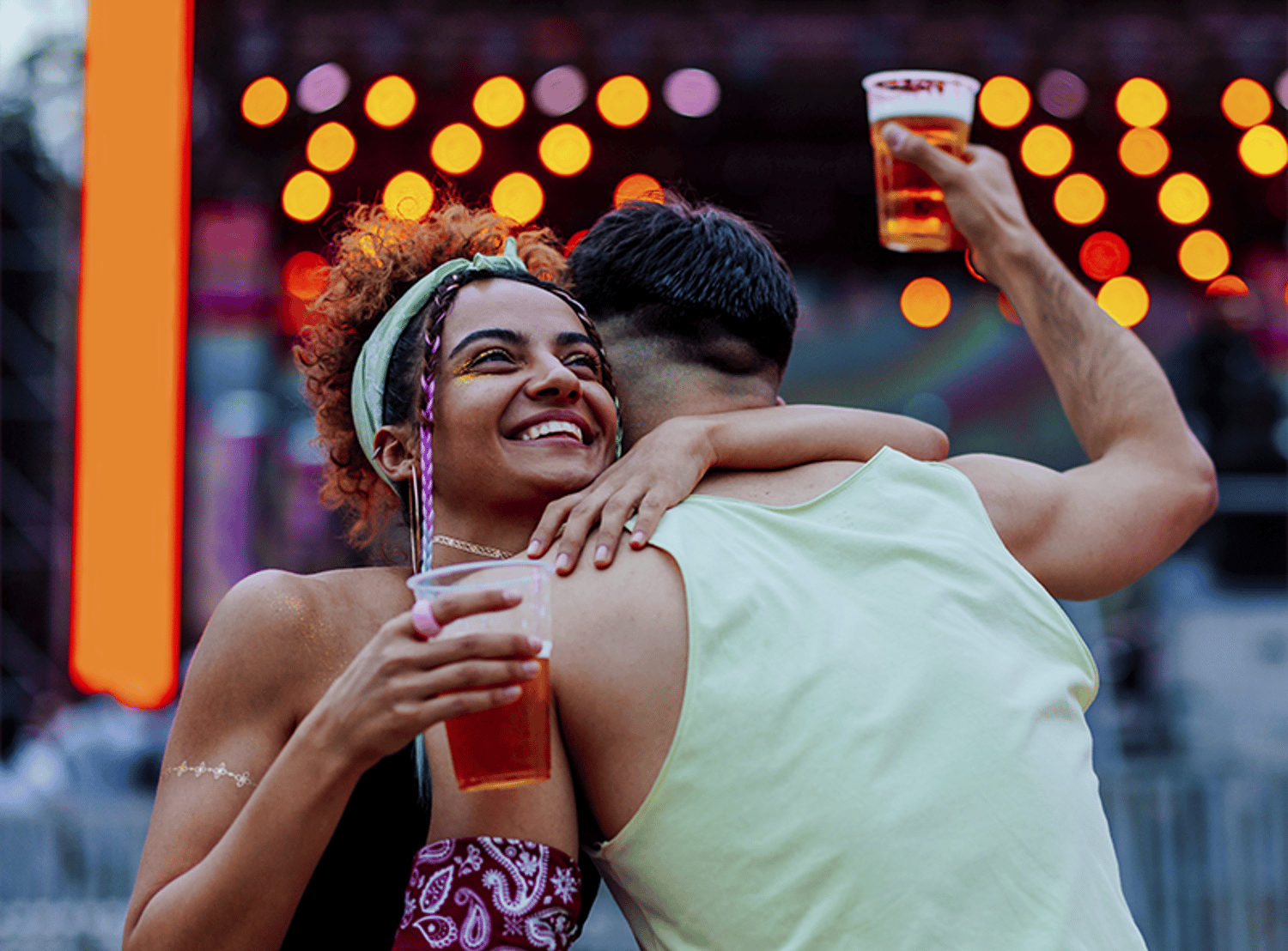 Image of two friends hugging, while holding beers