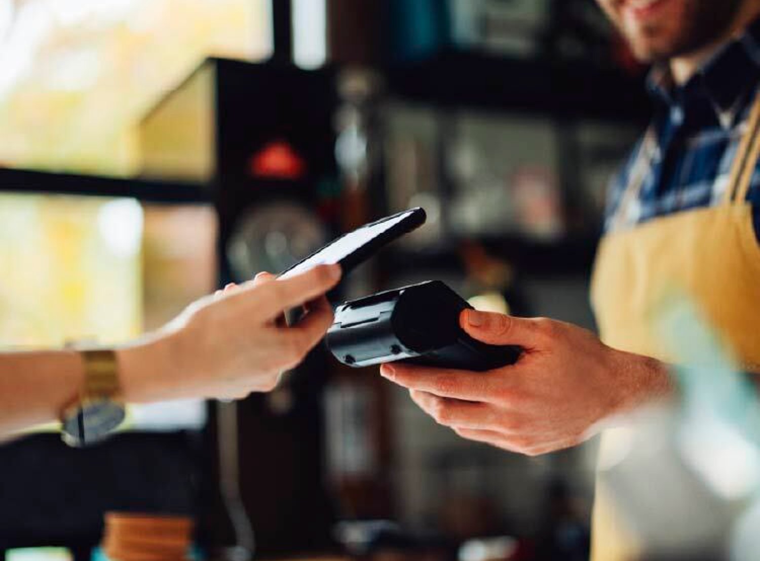 A hang tapping their mobile pay feature to a card reader in a store