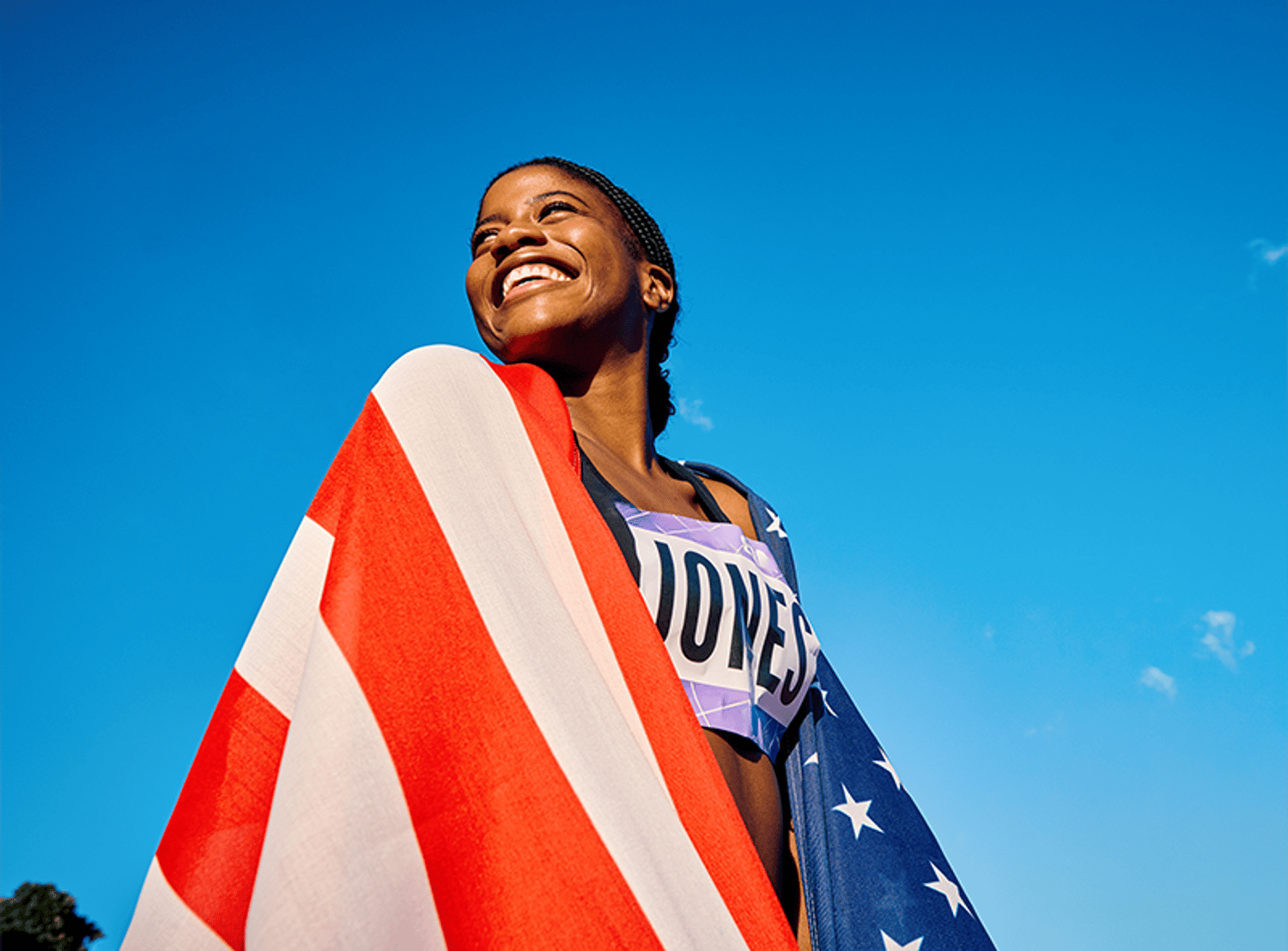 An olympian smiling and wrapped in the American flag