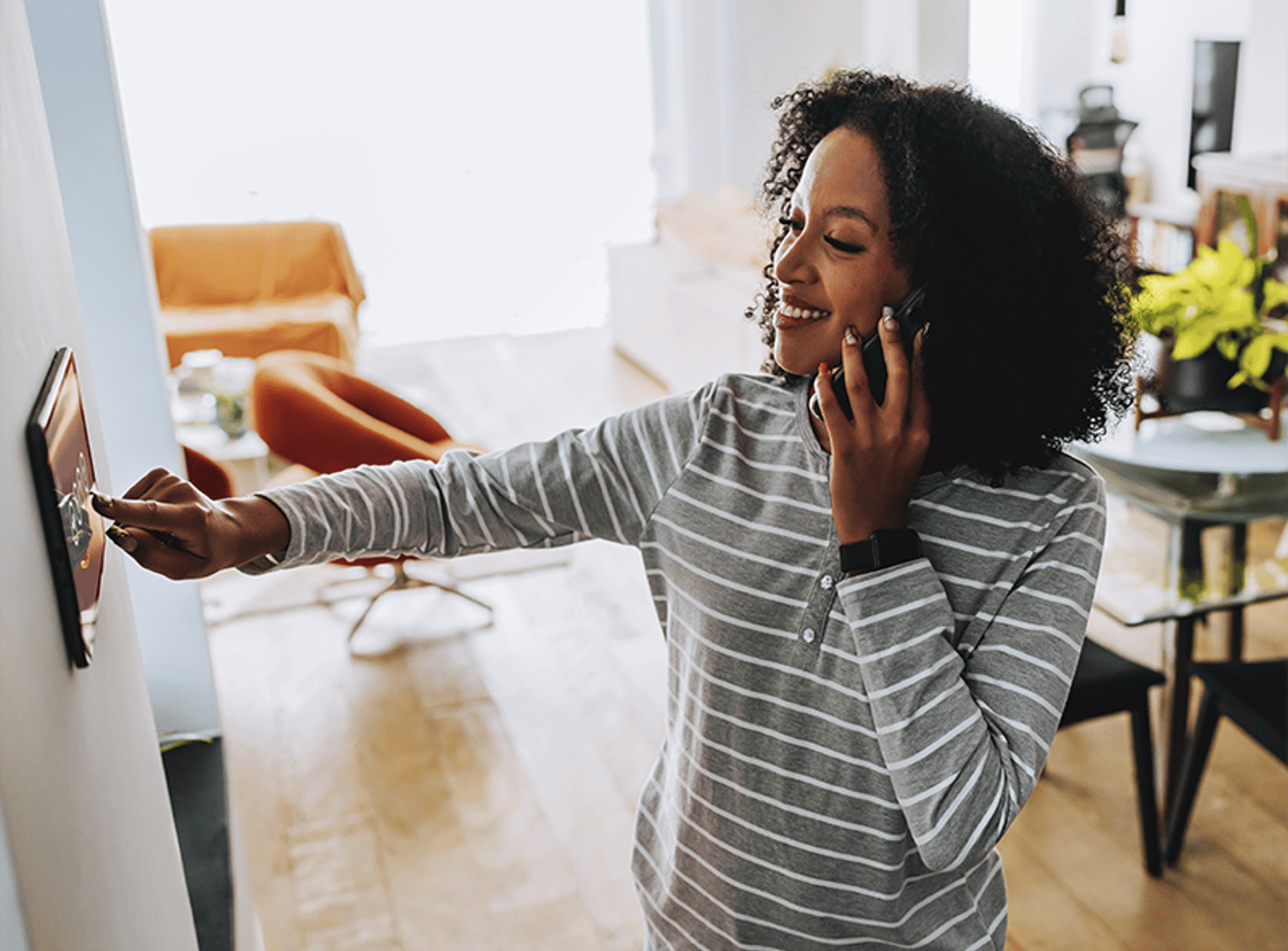 Woman speaking on a phone while clicking a wall unit