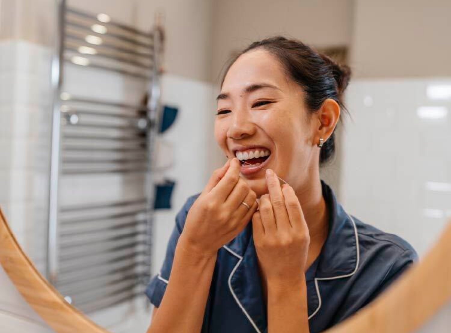 Woman flossing her teeth while in her bathroom