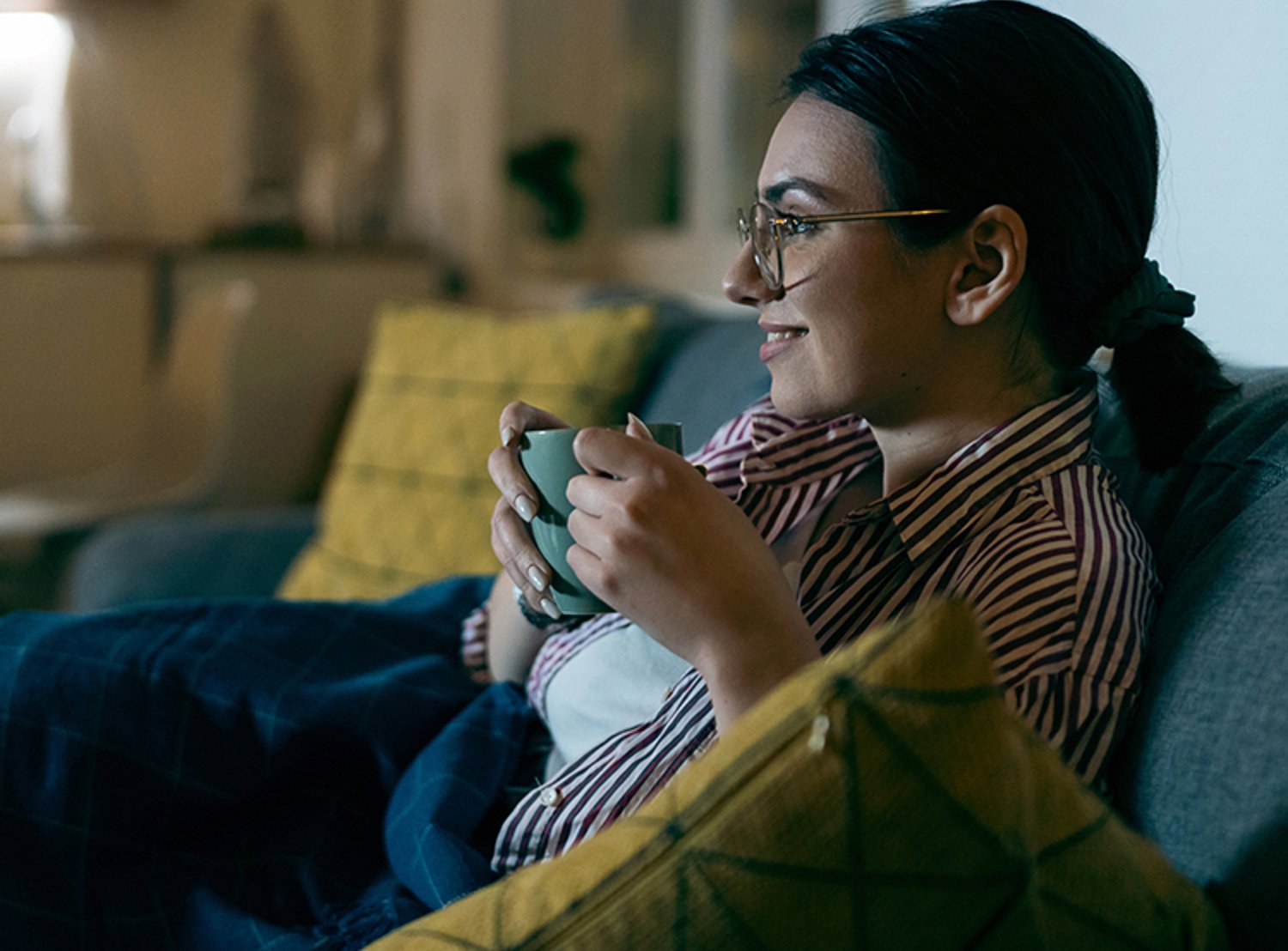 Woman holding a mug and watching television