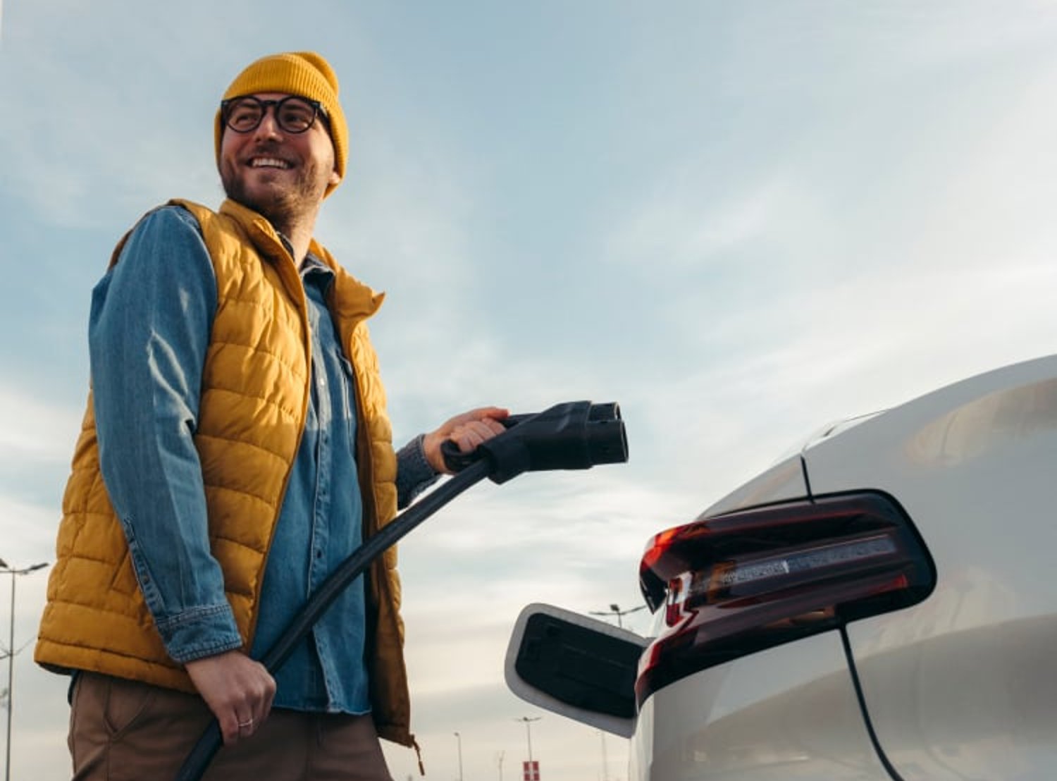 Image shows a man getting ready to charge his car. Audi, and PHD logos are featured at the top left corner of the image.