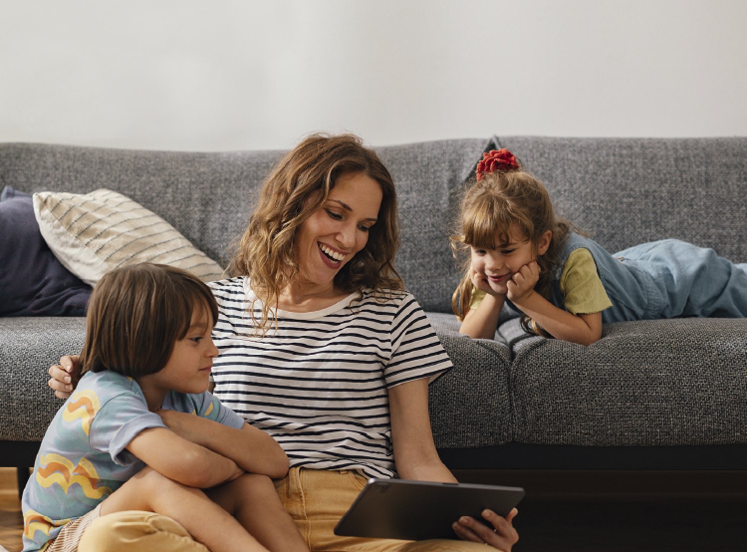 Image of a mom and her two kids, looking at a tablet