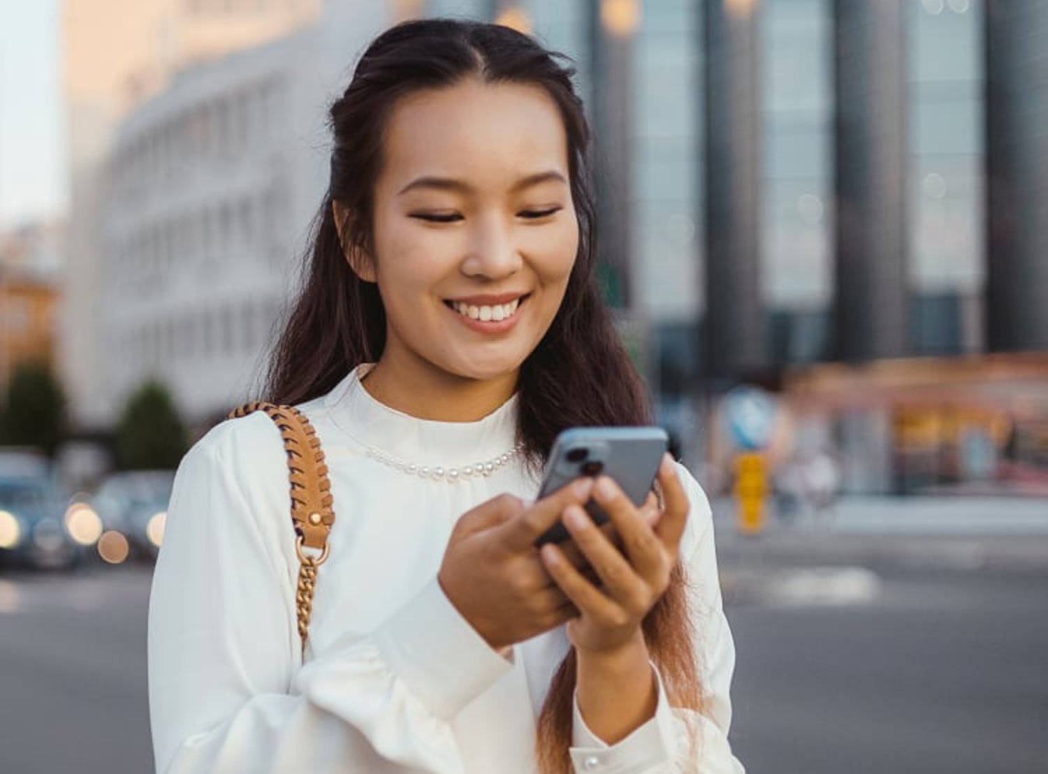 A smiling woman is seen holding her phone