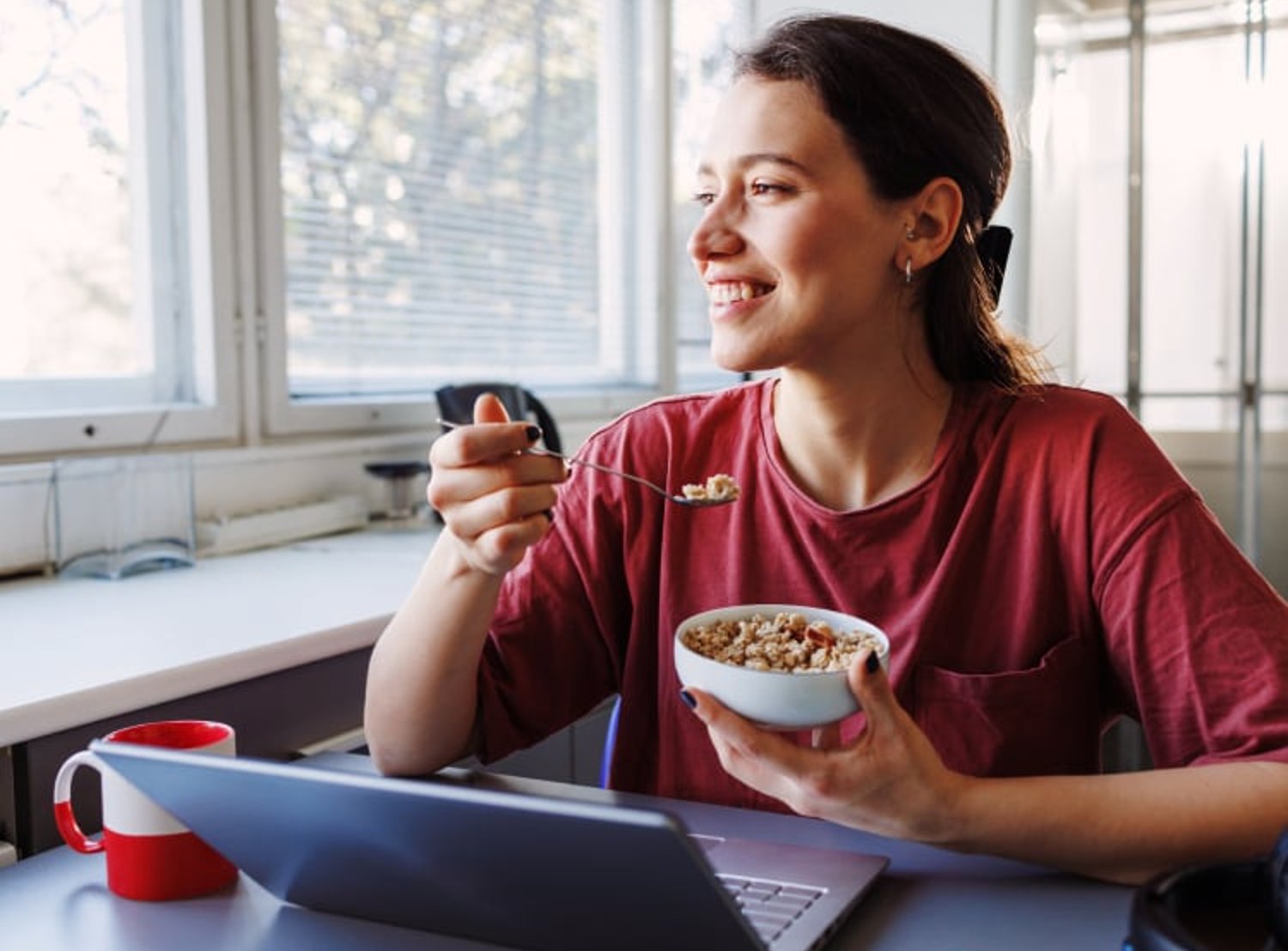 Image shows a woman eating a bowl of cereal