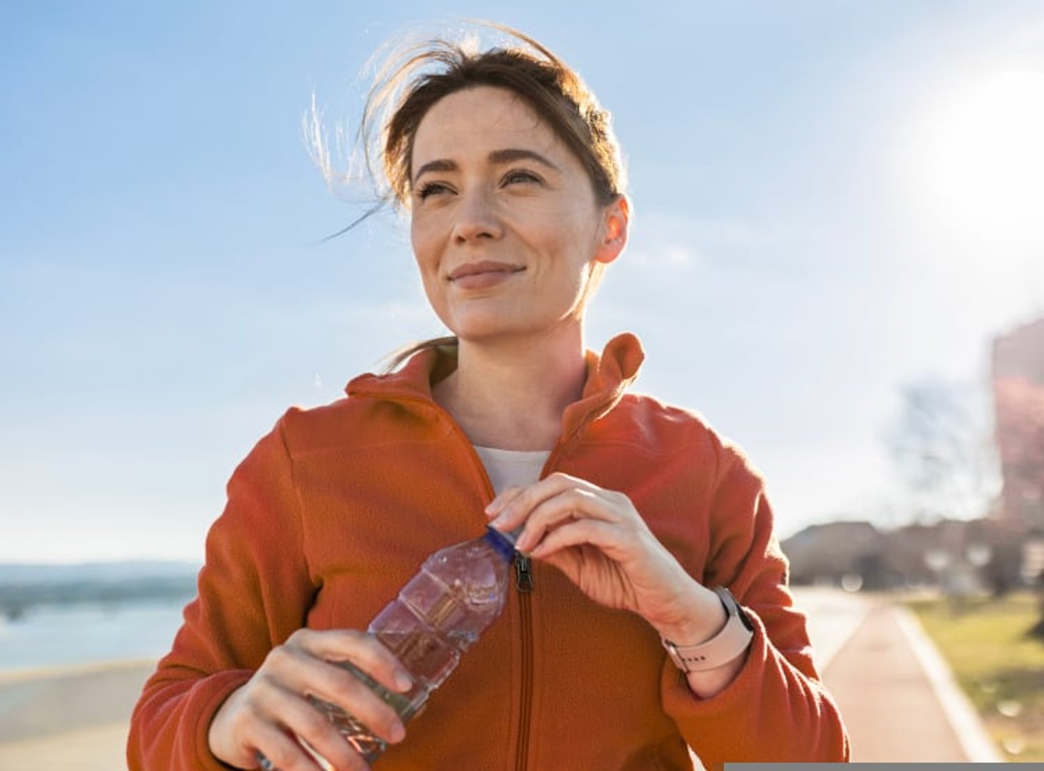 Image of a woman outside closing her water bottle and smiling