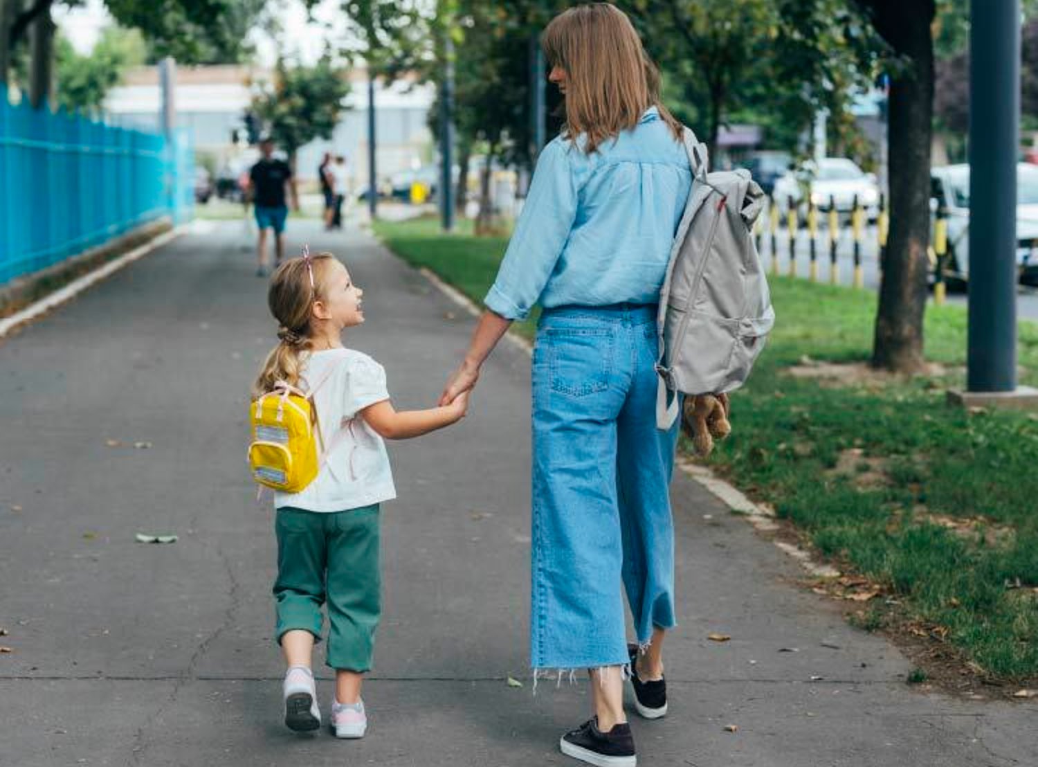 Mother and child walking to school while wearing backpacks