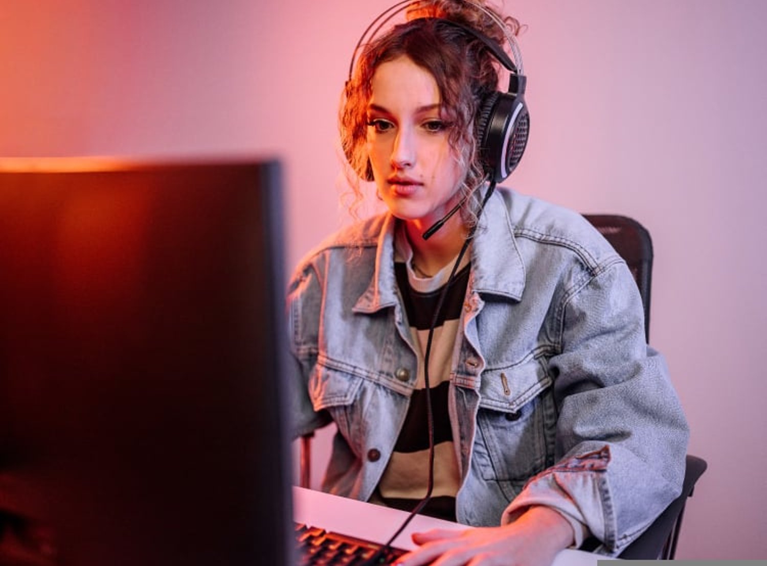 Woman gamer wearing headphones and looking concentrated at her computer