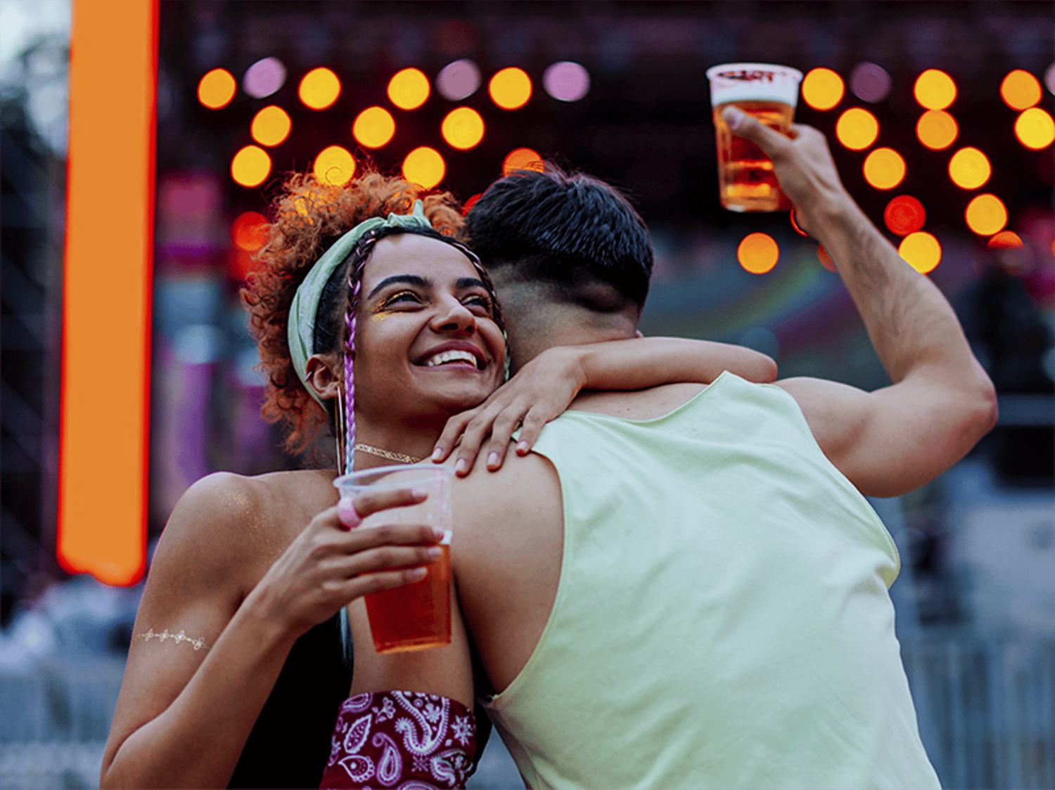 Bild von zwei Freund:innen, die sich umarmen und jeweils ein Bier in der Hand halten