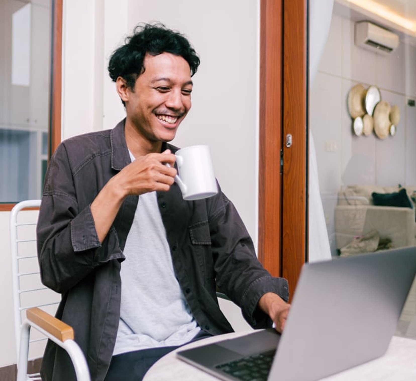 Man sitting at laptop holding a coffee cup