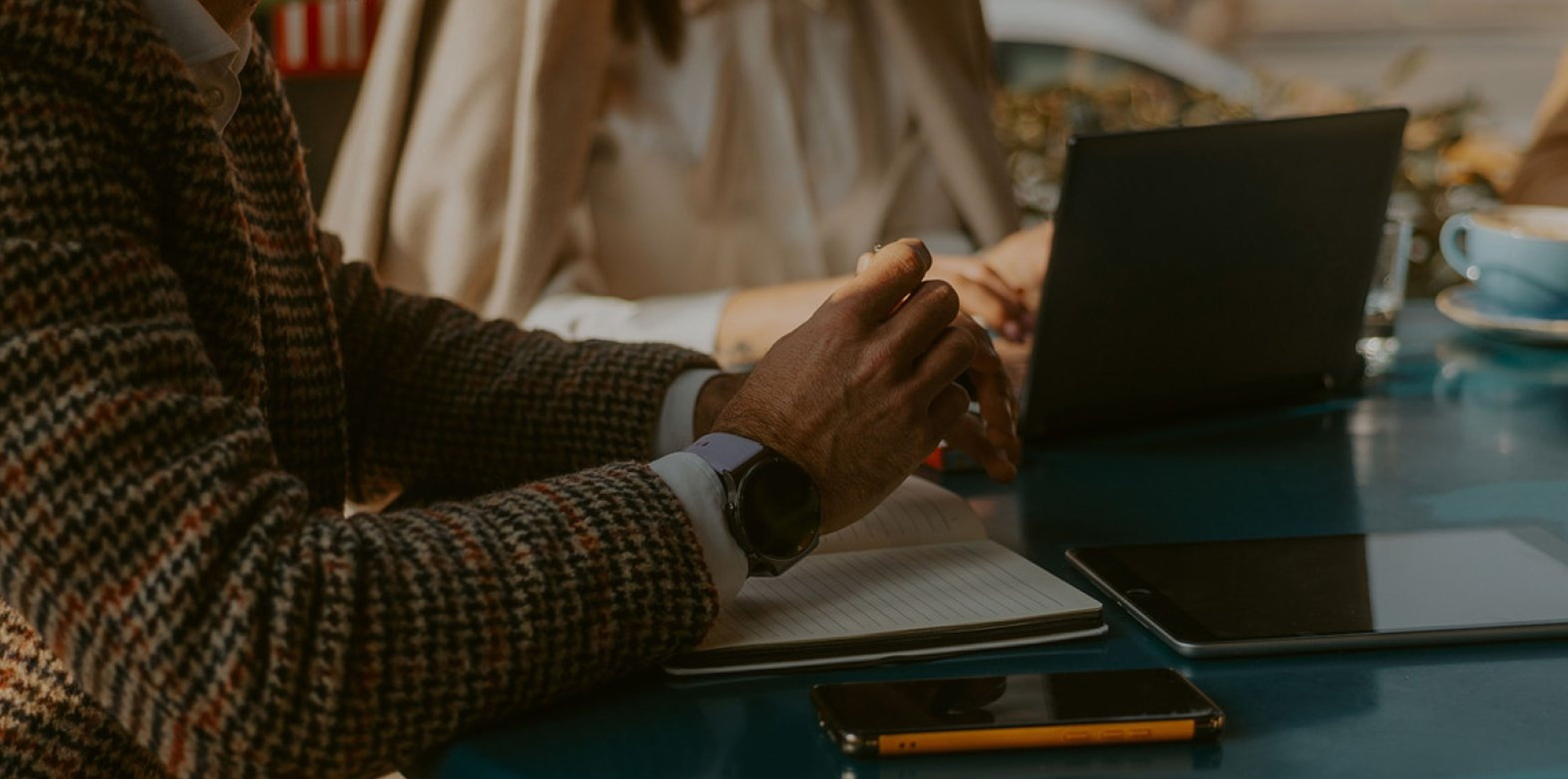 man with hands folded working with someone on a laptop