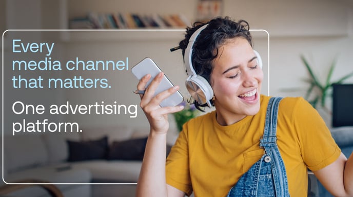 Woman wearing headphones and holding her phone with the text "Every media channel that matters. One advertising platform."