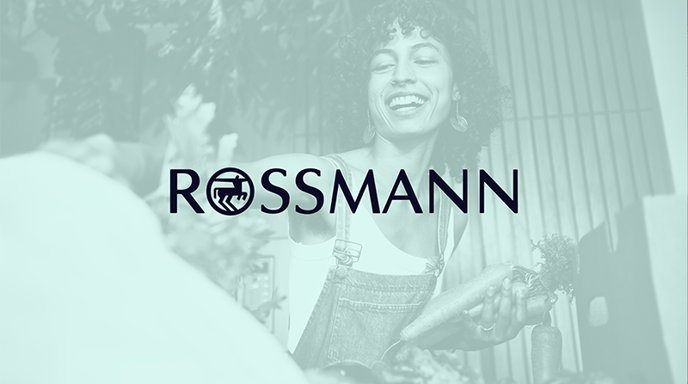 A woman wearing overalls, smiling and shopping for produce with a green wash and Rossman logo placed on top