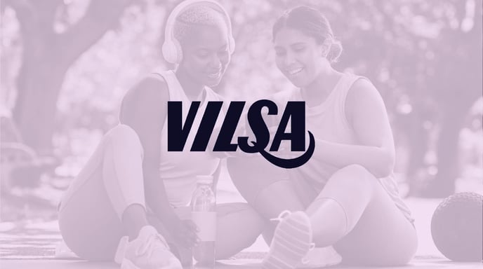 Two women in athletic wear sit outdoors, smiling and sharing a moment, overlaid with the "VILSA" logo in bold typography.