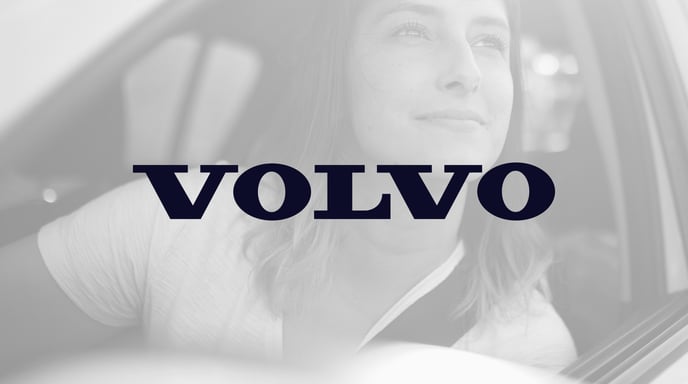 Woman smiling and looking out of the window of her Volvo SUV in black and white, with the Volvo logo in the center