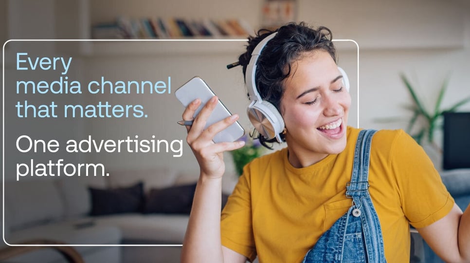 Woman wearing headphones and holding her phone with the text "Every media channel that matters. One advertising platform."