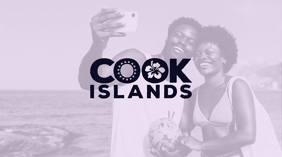 A promotional image with a soft-toned filter, featuring the Cook Islands logo over a background of a happy couple taking a selfie on the beach while holding a fresh coconut with straws.