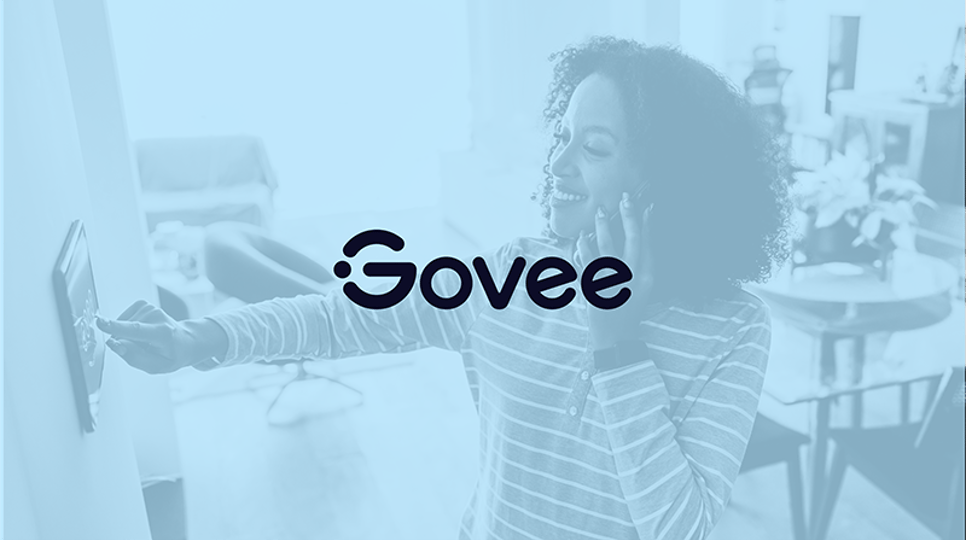 Woman speaking on a phone while clicking a wall unit with a blue wash over and the Govee logo in the center