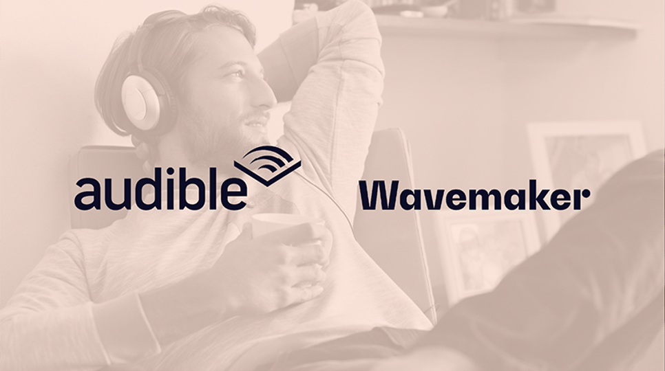 A man relaxing on a chair, wearing headphones and holding a cup, with a content expression, with an orange overlay and the Audible and Wavemaker logos in the center.